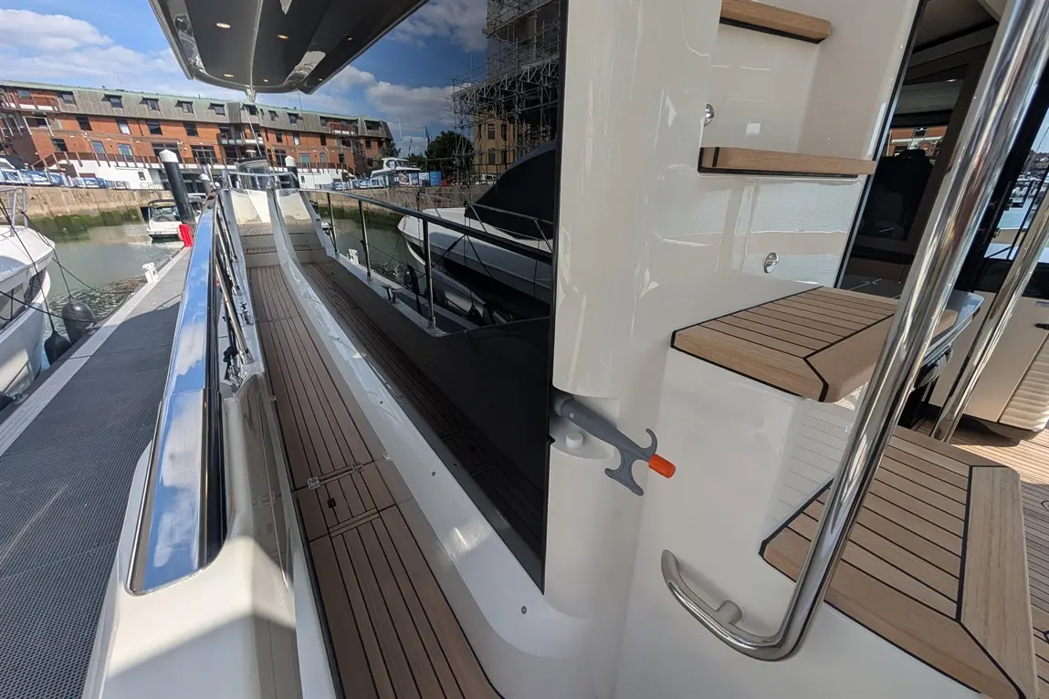 Interior view of a luxury yacht showing a polished deck, steps, and stylish railings with reflections in the water.
